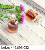 Flower thistles and extract from it. Buds medicinal wild plants burdock and burdocks medicinal tincture from it. Стоковое фото, агентство Ingram Publishing / Фотобанк Лори