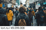 A large group of people march down a city street, carrying signs and banners. They are protesting for a cause that is not clear from the image. Стоковое AI-изображение, AI-художник Данила Большаков / Фотобанк Лори