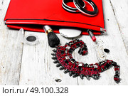 Red clutch bag and ladies accessories. Fashionable ladies handbag with cosmetics and decorations on light background. Стоковое фото, агентство Ingram Publishing / Фотобанк Лори