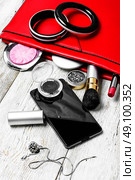 Red clutch bag and ladies accessories. Fashionable ladies handbag with cosmetics and phone on light background. Стоковое фото, агентство Ingram Publishing / Фотобанк Лори