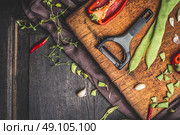 Green  beans cooking preparation with vegetables peeler on dark wooden background, top view, border. Стоковое фото, агентство Ingram Publishing / Фотобанк Лори