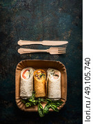Vegetarian wraps in paper plate and wooden cutlery on dark background, top view, place for text. Healthy lunch. Стоковое фото, агентство Ingram Publishing / Фотобанк Лори