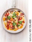 Egg omelette in white frypan with tomatoes,bread, cheese and sausage on white wooden background, top view, close up. Стоковое фото, агентство Ingram Publishing / Фотобанк Лори