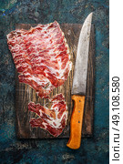 Smoked pork meat from coppa with kitchen knife on rustic wooden background. Traditional Italian specialty made from pork neck . Top view. Стоковое фото, агентство Ingram Publishing / Фотобанк Лори