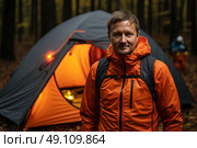 Solitary Wanderer: A Pensive Man Contemplates His Journey in Front of a Rustic Tent Amidst the Enchanted Woods. Стоковое AI-изображение, AI-художник Данила Большаков / Фотобанк Лори