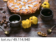 Pie with autumn quinces. Autumn pie with slices of quince and warming cup of tea. Стоковое фото, агентство Ingram Publishing / Фотобанк Лори