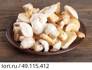 Edible wild mushrooms on a wooden background. Forest cleaned mushrooms in a clay plate. Стоковое фото, агентство Ingram Publishing / Фотобанк Лори