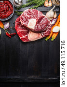 Veal shank slices meat and ingredients for Osso Buco cooking on dark wooden background,  top view, vertical border. Стоковое фото, агентство Ingram Publishing / Фотобанк Лори