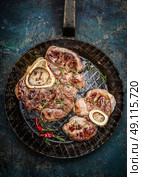 Roasted veal shank slices in frying pan on rustic background, top view, close up. Стоковое фото, агентство Ingram Publishing / Фотобанк Лори
