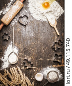 Christmas baking background with ingredients and  tools: Cookie Cutters, Cups, Mats, Rolling Pin, spoon . Dark, rustic, top view, frame. Стоковое фото, агентство Ingram Publishing / Фотобанк Лори