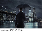 Young manager with an umbrella over the night city background. Стоковое фото, агентство Ingram Publishing / Фотобанк Лори