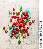 Tasty red cherries with leaves in blue bowls and table, top view composing. Summer fruit  and berries concept. Стоковое фото, агентство Ingram Publishing / Фотобанк Лори