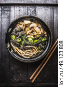 Asian ramen soup with noodles, tofu and nori seaweed in bowl with Chopsticks on dark wooden background. Стоковое фото, агентство Ingram Publishing / Фотобанк Лори