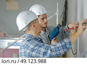 group of builders in hardhats with electric drill indoors. Стоковое фото, агентство Ingram Publishing / Фотобанк Лори