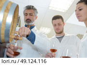 group wearing coats holding glass of wine in cellar. Стоковое фото, агентство Ingram Publishing / Фотобанк Лори