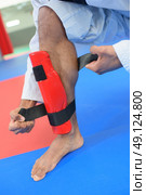 Martial artist attaching leg guard. Стоковое фото, агентство Ingram Publishing / Фотобанк Лори