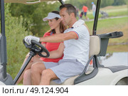 couple driving golf buggy on golf course. Стоковое фото, агентство Ingram Publishing / Фотобанк Лори