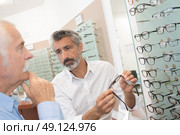 middle-age male ophthalmologist helping customer to choose glasses. Стоковое фото, агентство Ingram Publishing / Фотобанк Лори