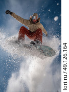 A snowboarder is in mid-air, with his board and snow flying around him. Стоковое AI-изображение, AI-художник Ярославский Максим / Фотобанк Лори