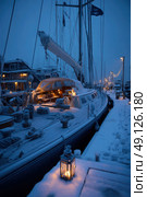 A boat is docked at a pier with a lantern lit on the deck. Стоковое AI-изображение, AI-художник Ярославский Максим / Фотобанк Лори