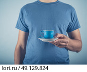 A young man wearing a blue t-shirt is holding a cup of espresso. Стоковое фото, агентство Ingram Publishing / Фотобанк Лори