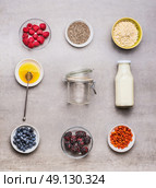 Healthy breakfast  ingredients : honey, oatmeal , Chia seeds, Goji berries, fresh berries and bottle of milk  with empty glass on gray background, top view, flat lay. Стоковое фото, агентство Ingram Publishing / Фотобанк Лори
