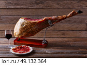 Iberian ham pata negra from Spain with red wine on wood background. Стоковое фото, агентство Ingram Publishing / Фотобанк Лори
