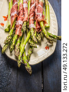 Green asparagus with parma ham in plate on rustic blue wooden background, close up. Стоковое фото, агентство Ingram Publishing / Фотобанк Лори