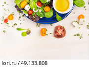 Salad with tomatoes, feta cheese and oil vinegar in blue plate on white wooden background, top view frame. Стоковое фото, агентство Ingram Publishing / Фотобанк Лори