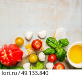 Tomatoes, mozzarella balls with basil leaves and oil in white bowl on rustic wooden background, top view, place for text. Стоковое фото, агентство Ingram Publishing / Фотобанк Лори