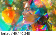 Woman with closed eyes peacefully basks in sunlight while surrounded by colorful, prismatic reflections from glass in an outdoor setting. Стоковое AI-изображение, AI-художник Данила Большаков / Фотобанк Лори