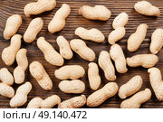 Peanuts in shell scattered on a wooden table. Background with nuts. Стоковое фото, агентство Ingram Publishing / Фотобанк Лори