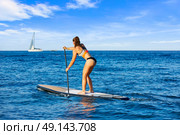SUP Stand up Surf girl with paddle in a blue ocean sea. Стоковое фото, агентство Ingram Publishing / Фотобанк Лори