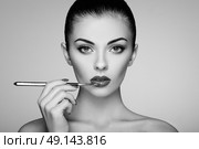 Black and white photo of woman painting lipstick. Beautiful woman face. Makeup detail. Beauty girl with perfect skin. Red lips and nails manicure. Стоковое фото, агентство Ingram Publishing / Фотобанк Лори