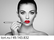 Black and white photo of woman painting lipstick. Beautiful woman face. Makeup detail. Beauty girl with perfect skin. Red lips and nails manicure. Стоковое фото, агентство Ingram Publishing / Фотобанк Лори