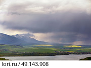 Town on the lake behind the foothills. Spring rain and storm in mountains. Green spring hills of Slovakia. Spring stormy scene. Стоковое фото, агентство Ingram Publishing / Фотобанк Лори