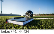 Notebook with pen resting on green field, blurred helmet and stadium in background under clear sky. Sunlight casts long shadows, emphasizing open space and sports atmosphere. Стоковое AI-изображение, AI-художник Ольга Невская / Фотобанк Лори