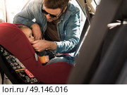 Father fasten his little baby in the car seat. Стоковое фото, агентство Ingram Publishing / Фотобанк Лори