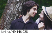 A young guy is waiting for his beloved girl by a tree in the forest. She closes his eyes from behind and they kiss. Стоковое видео, видеограф Ярославский Максим / Фотобанк Лори