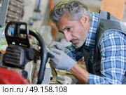 Mechanic working on gardening equipment. Стоковое фото, агентство Ingram Publishing / Фотобанк Лори