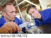 Tutor using vernier guage, apprentice watching. Стоковое фото, агентство Ingram Publishing / Фотобанк Лори