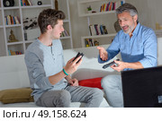 Father and son in disagreement over remote control. Стоковое фото, агентство Ingram Publishing / Фотобанк Лори
