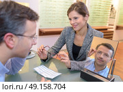 beautiful optician helping male customer choosing eye glasses. Стоковое фото, агентство Ingram Publishing / Фотобанк Лори