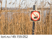 Fishing sign by a river with tall reeds with a caught fishing symbol with a no fishing warning. Стоковое фото, агентство Ingram Publishing / Фотобанк Лори