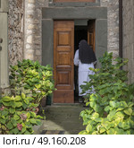 Rear view of nun entering in chapel, Radda in Chianti, Tuscany, Italy. Стоковое фото, агентство Ingram Publishing / Фотобанк Лори