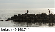 Men on rock groyne by sea, Sant'Angelo, Ischia Island, Campania, Italy. Стоковое фото, агентство Ingram Publishing / Фотобанк Лори