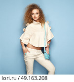 Fashion portrait of woman in summer outfit. Girl posing on pink background. Blue handbag. Stylish curly hairstyle. Glamour lady. Стоковое фото, агентство Ingram Publishing / Фотобанк Лори