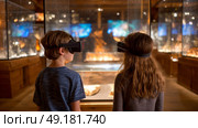 Child using virtual reality headset for metaverse, child looking into VR glasses. Little girl boy with futuristic glasses having fun, teenager playing video games. Technology, simulator, oculus future. Стоковое AI-изображение, AI-художник ALLA YURTAYEVA / Фотобанк Лори