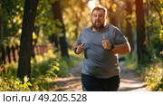 Overweight man in motion, running down a path surrounded by trees in a forest setting. Стоковое AI-изображение, AI-художник Данила Большаков / Фотобанк Лори