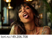 A woman standing with her eyes closed and tongue sticking out in a playful manner. Стоковое AI-изображение, AI-художник Данила Большаков / Фотобанк Лори
